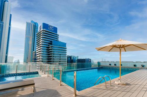 迪拜FAM Living - Mada Residences Downtown Dubai的一座带遮阳伞的建筑屋顶上的游泳池