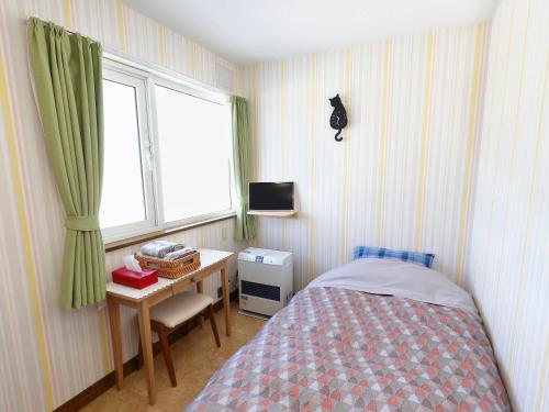 美瑛町Pension Ken&Mary的一间卧室配有一张床、一张书桌和一个窗户。