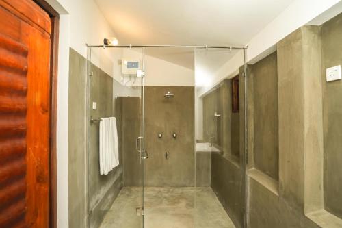 汉班托塔Malala Retreat的浴室里设有玻璃门淋浴