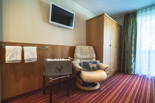 圣加伦基希Alpenherz Apartments的酒店客房设有椅子和电视。
