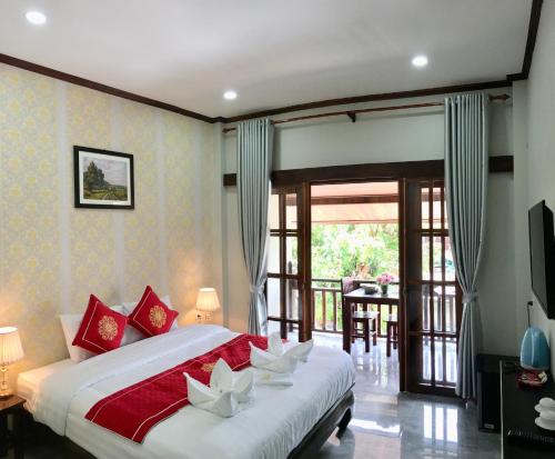琅勃拉邦Le KhounSok Boutique Hotel的一间卧室配有一张带红色和白色枕头的大床