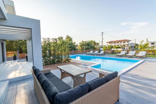佩科霍里Assos Luxury Villas的游泳池旁带桌椅的天井