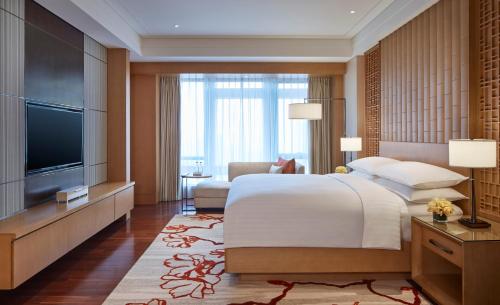 珠海珠海新骏景万豪酒店的一间卧室配有一张大床和一台平面电视