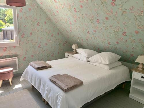 AudervilleMaison Bord de Mer dans la Petite Irlande的一间卧室配有一张带白色床单和花卉壁纸的床