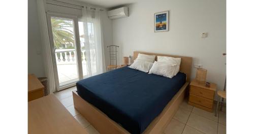 艾姆布里亚布拉瓦Cap Ras的一间卧室配有一张带蓝色床单的床和一扇窗户。