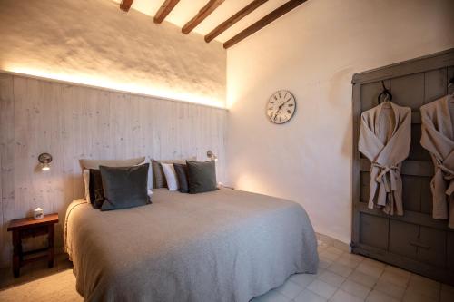 卡尔维亚Agroturismo Son Boronat的卧室配有一张床,墙上挂着一个钟