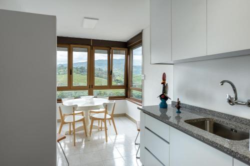 比索达雷加Apartamento T3 - D'ouro a Vista的厨房配有白色橱柜和桌椅