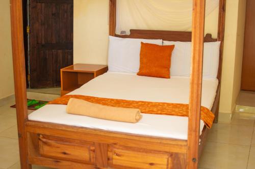 KikambalaMsafiri Bed & Breakfast的一间卧室配有木制双层床、白色床单和橙色枕头