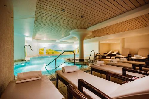 文尼斯塔特Lindner Hotel Sylt的酒店设有一个游泳池和桌椅