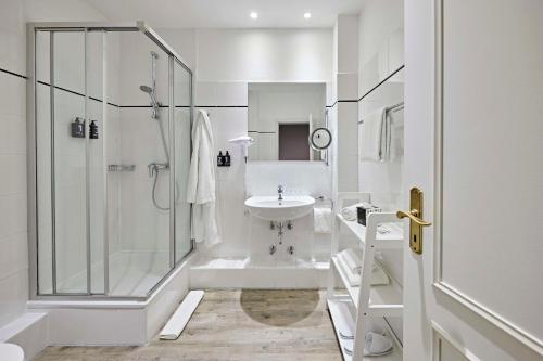 文尼斯塔特Lindner Hotel Sylt的带淋浴和盥洗盆的白色浴室