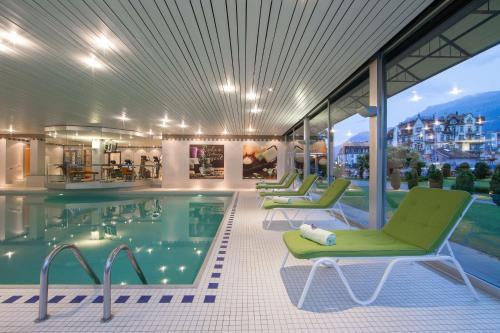 因特拉肯Grand Hotel Beau Rivage Interlaken的一座带绿色躺椅的酒店游泳池