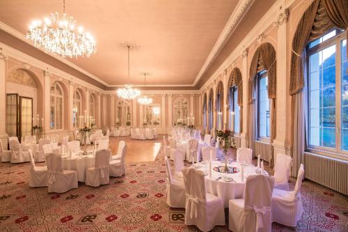 因特拉肯Grand Hotel Beau Rivage Interlaken的宴会厅配有白色的桌椅和吊灯