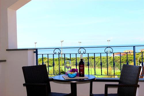 卡斯特尔萨多玫瑰之风酒店的阳台上的桌子和一瓶葡萄酒