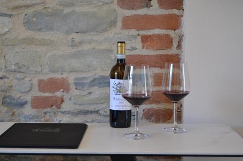 迪亚诺达尔巴Le Cornici - Cascina di Charme的桌子上放有一瓶葡萄酒和两杯酒
