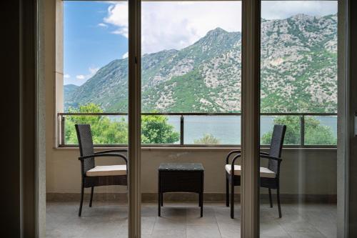 里桑Apartmani na Plaži的窗户前设有2把椅子和1张桌子的房间
