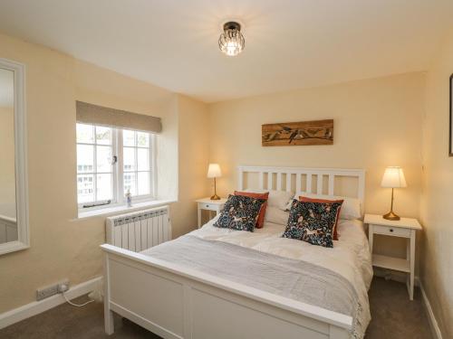 莱奇莱德Wharf Cottage的一间卧室配有一张白色床、两盏灯和两扇窗户。