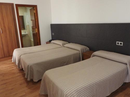 罗列特海岸拉帕尔梅拉酒店和spa的配有带条纹床单的酒店客房内的3张床