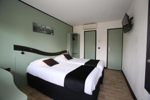 沙特尔Enzo Hotels Chartres Mainvilliers by Kyriad Direct的一间卧室配有一张带白色和黑色床单的大床