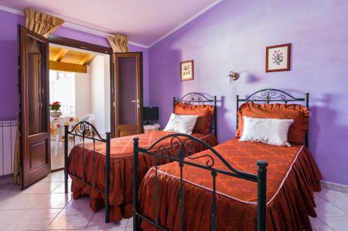 卡布拉斯Casa Titti的卧室设有两张床铺和紫色墙壁