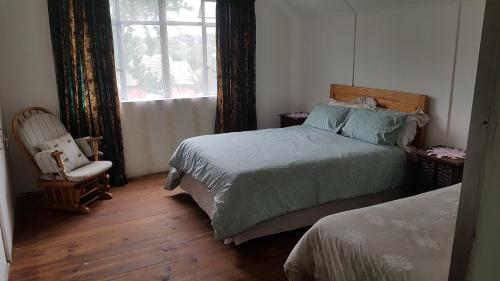 彼得马里茨堡Crafty Coal Stove的一间卧室设有两张床、一把椅子和一个窗户。