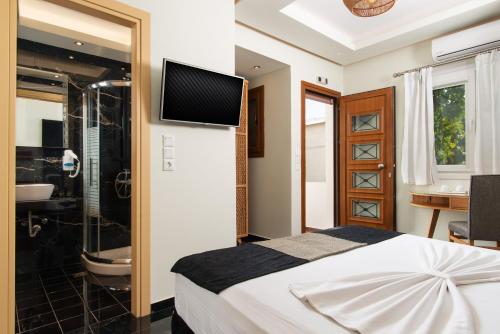 阿达玛斯Angelica's Deluxe Rooms in Adamas的一间卧室配有一张床、淋浴和一台电视