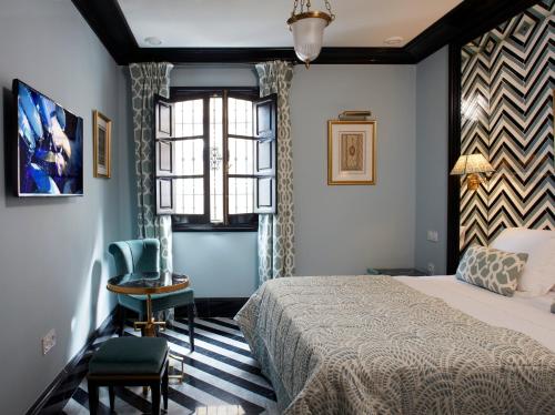 塞维利亚Triana House的一间卧室设有一张床、一个窗口和一把椅子