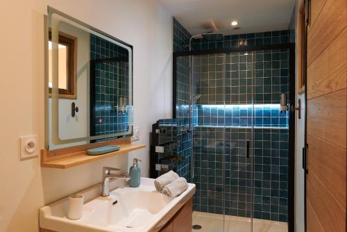克卢尼La Porte des Prés的浴室设有水槽和蓝色瓷砖淋浴。