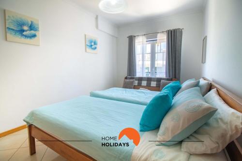 阿尔布费拉#101 Kid Friendly with Pool, Private Park, 400 mts Beach的一间卧室配有一张带蓝色枕头的床和一扇窗户。