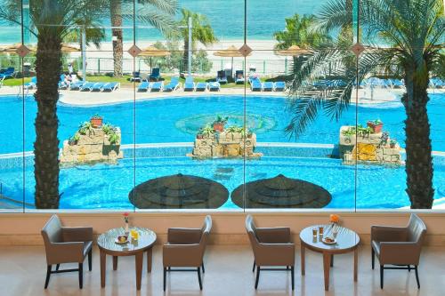 恩波其克死海莱昂纳多广场酒店的餐厅设有桌椅,享有游泳池的景色。