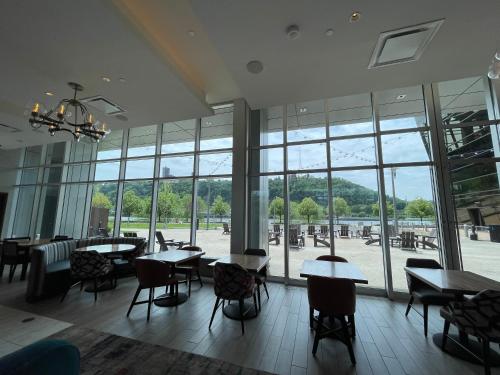 匹兹堡The Landing Hotel at Rivers Casino Pittsburgh的餐厅设有桌椅和大窗户。
