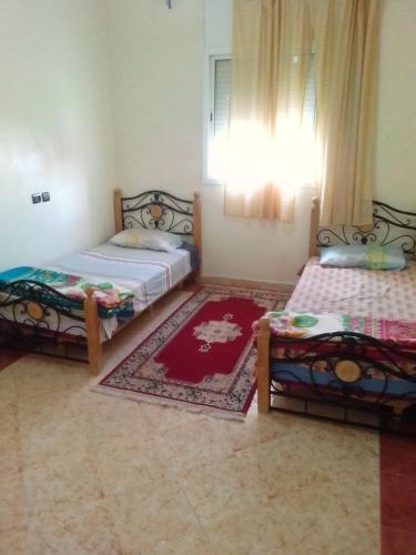 Attaouiya ech ChaïbiyaApartments in Attaouia Wonderful的一间带两张床的卧室和红色地毯