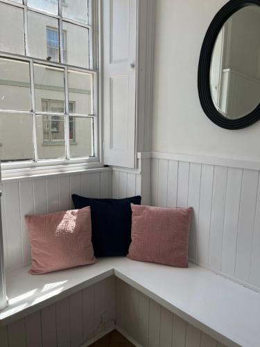 瓦伊河畔罗斯6 Wye Valley Chambers, Ross-on-Wye的配有两个枕头和镜子的客房内的长凳