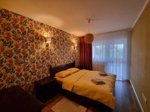 圣格奥尔基Bougainvillea Apartman的一间卧室配有一张带花卉壁纸的床