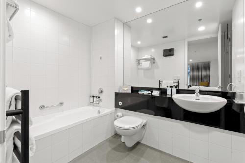 皇后镇美景酒店的白色的浴室设有水槽、卫生间和浴缸。