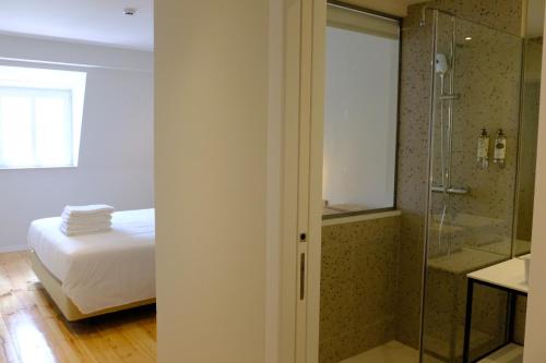 里斯本Liberator Rossio的一间卧室设有一张床和一个玻璃淋浴间