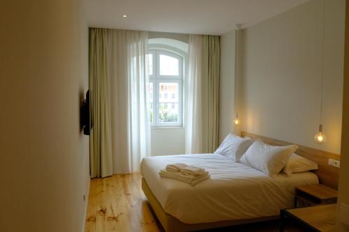 里斯本Liberator Rossio的一间卧室配有一张带白色床单的床和一扇窗户。
