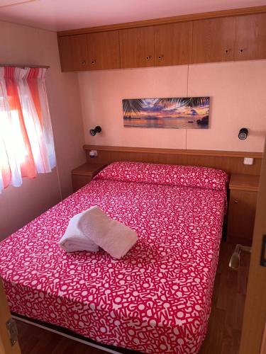 圣卡洛斯拉腊皮塔Chalet-home familiar "CAL DENVER" "Pet friendly"的一间卧室配有红色的床,上面有一条白色毛巾