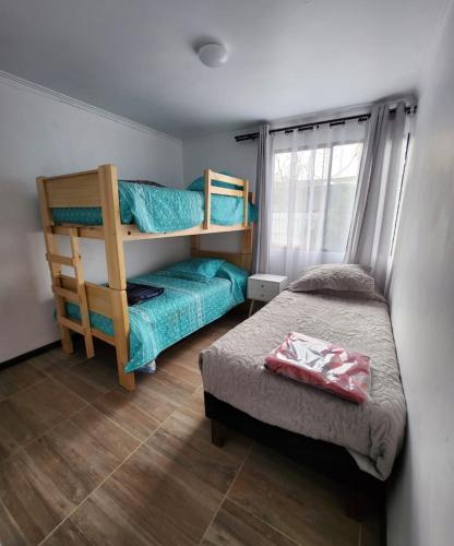 埃尔基斯科Casa en condominio cerca de la playa El Quisco Norte的一间卧室配有一张双层床、一张床和一个窗户。
