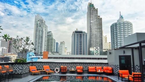 曼谷Ramada by Wyndham Bangkok Sukhumvit 11的一个带橙色椅子的屋顶露台,享有城市美景