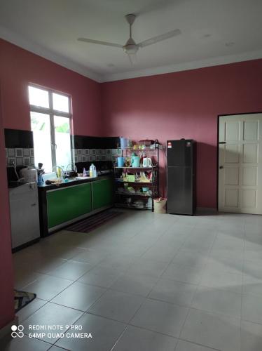 Kampong PauhHomestay Anjung Ismail Anjung Rahmah的厨房设有红色的墙壁和冰箱。