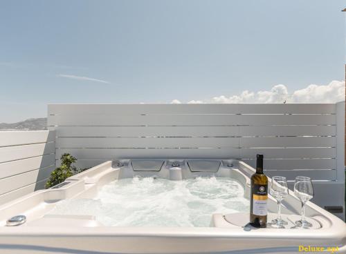 阿吉奥斯普罗科皮奥斯Aphrodite Luxury Apartments的热水浴池,配有一瓶葡萄酒和玻璃杯