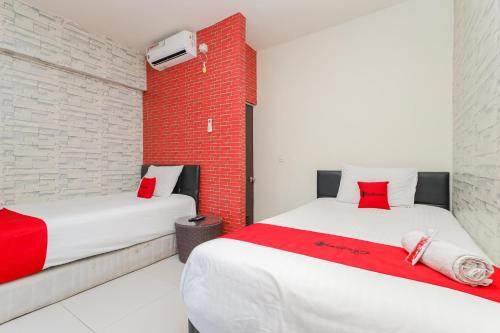 贝克西RedDoorz Syariah near Green Park Jatiwarna的红色砖墙客房的两张床