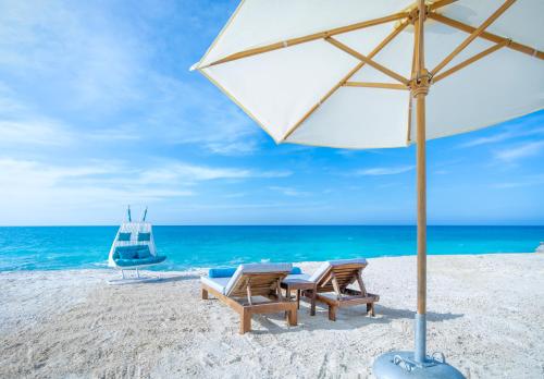 阿莱曼X Eastern Sidi Abdel Rahman Hotel的海滩上的两把椅子和一把遮阳伞