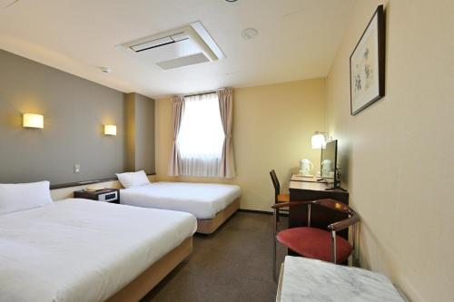 和歌山和歌山第二富士酒店的酒店客房 - 带两张床、一张桌子和一把椅子