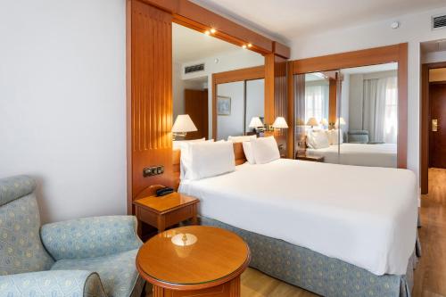 塞维利亚艾克斯塞维利亚玛卡瑞纳酒店的酒店客房配有床、桌子和沙发。