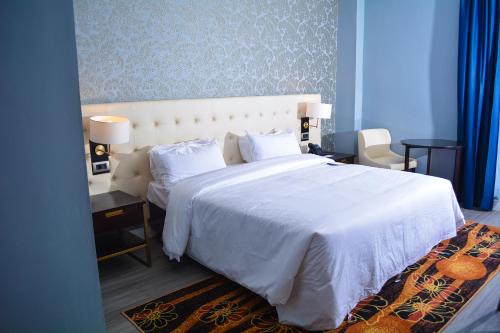 雅温得Djeuga Palace Hotel的一间卧室配有一张带白色床罩和枕头的床。