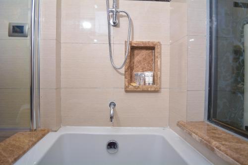 雅温得Djeuga Palace Hotel的带淋浴和水槽的白色浴缸