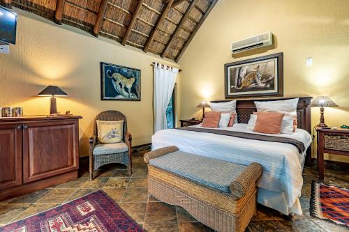 马里兰Mhlati Guest Cottages的一间卧室配有一张大床和一把椅子