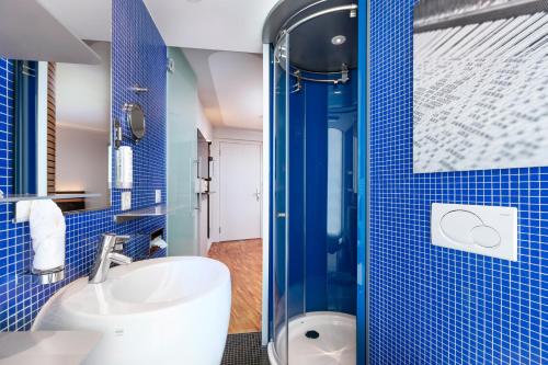 塔尔维尔塞达提斯瑞士品质酒店的蓝色瓷砖浴室设有水槽和淋浴