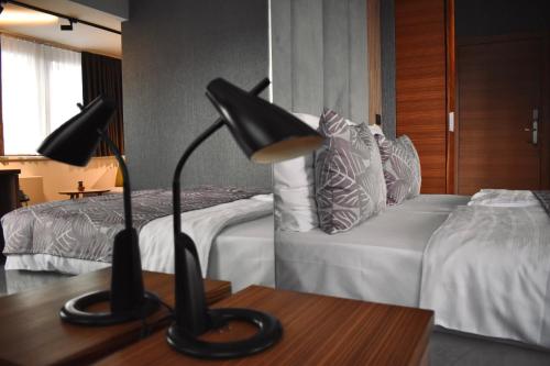 萨拉热窝Hotel City View Deluxe的一间卧室设有两张床和一张桌子上的台灯。